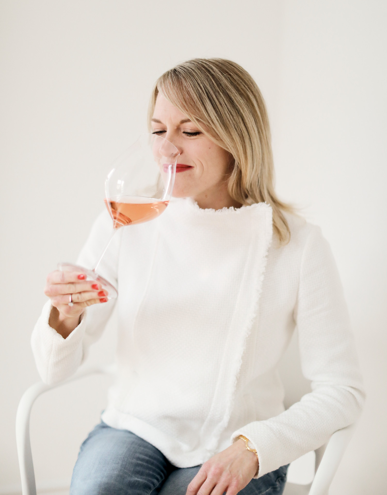 Kristin Perrin Sommelier and storyteller photo in white sweater with wine